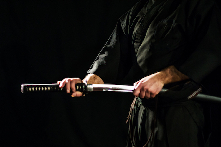 Uomo che tiene in mano spada tradizionale giapponese e pratica laido Kenjutsu.